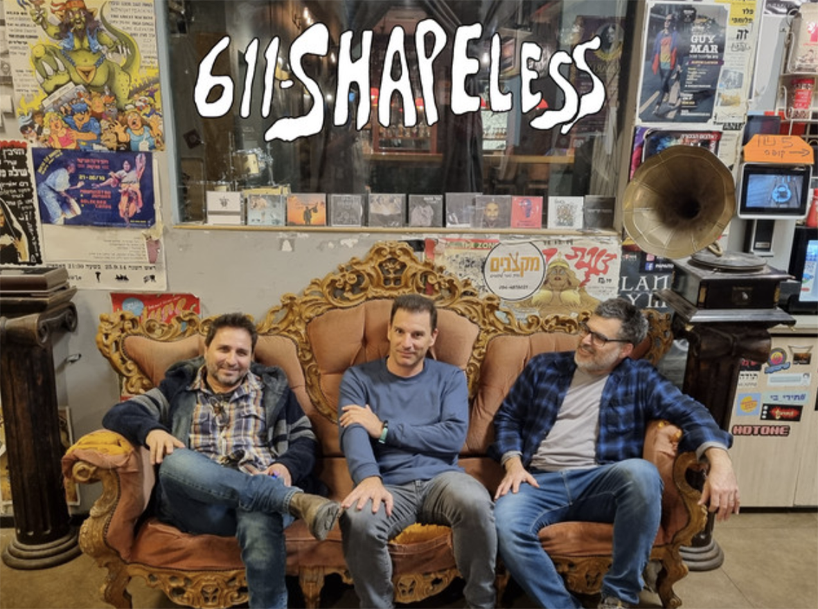 611 Shapeless — שלושת חברי ההרכב יושבים על ספה ותיקה מול קיר כרזות